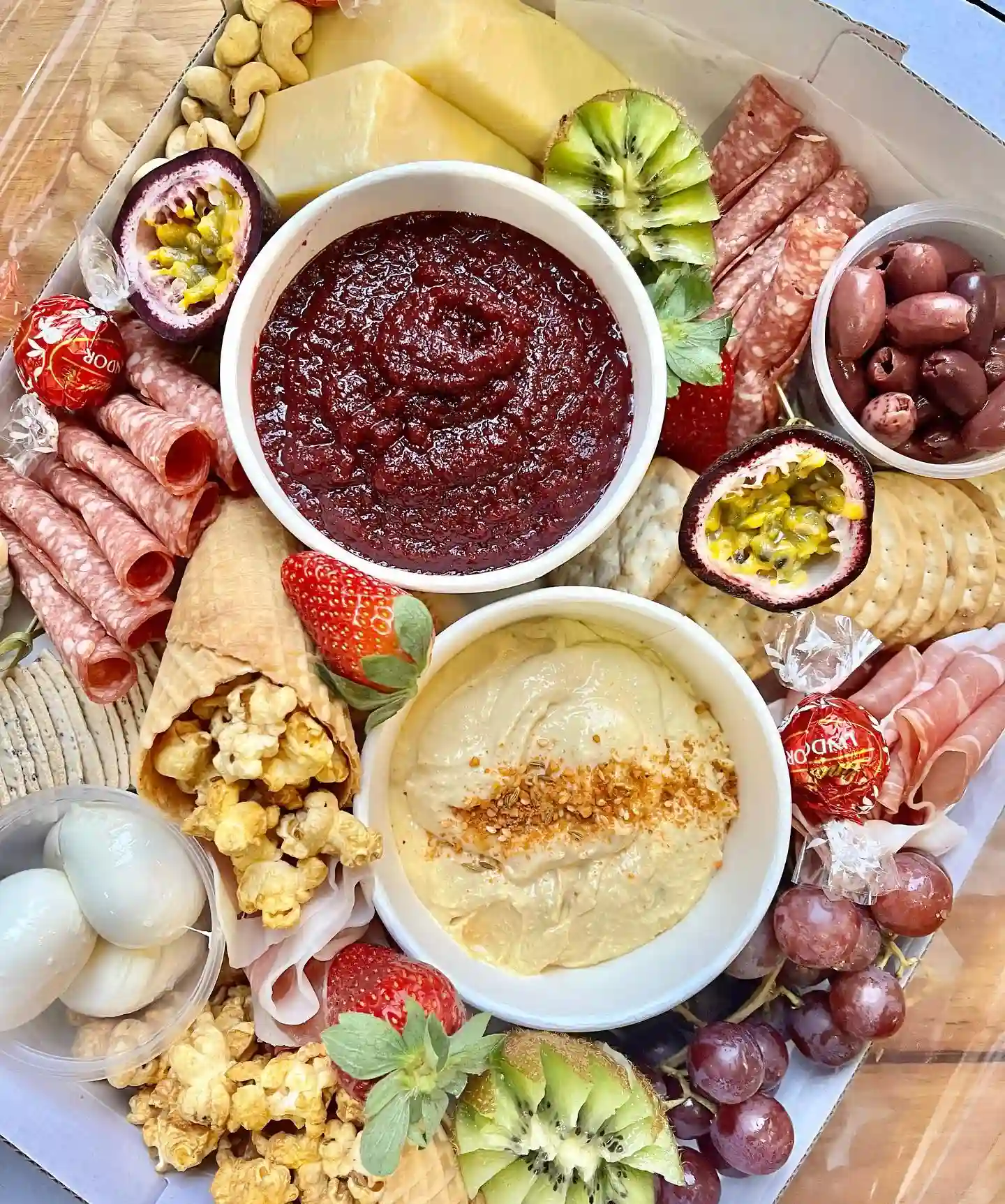 Charcuterie board containing an assortment of high quality cold meats paired with a selection of vintage cheeses, some housemate dips and divine chocolates and sweets